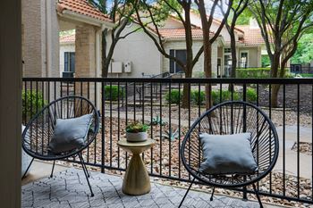 A balcony with two chairs and a table with a pillow